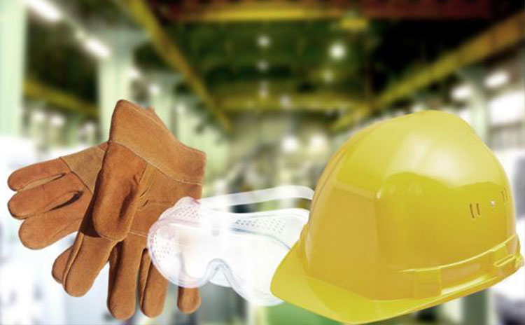Guantes, lentes y casco industrial, con una industria de fondo